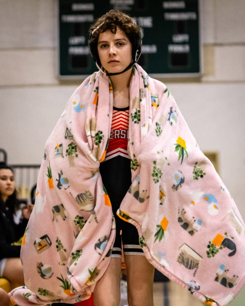 Image of Amber Chatterton, 109-pound wrestler from Bakersfield College warming up and wearing a blanket before her match.
