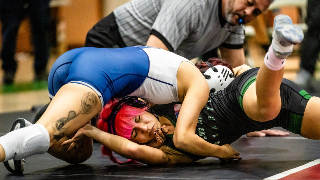 Mollie Jimenez, Freshman, East Los Angeles College vs Lucy Guadarrama, Sophomore Cerritos College. in a 109-pound weight class wrestling match at the ELAC South Gym. Here, Guadarrama is on top of Jimenez trying to pin her to the wrestling mat.